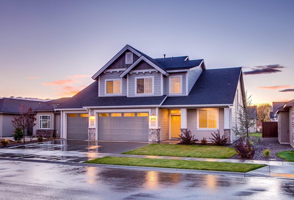 A residential suburban house exterior showing a garage, driveway, and neighborhood street.